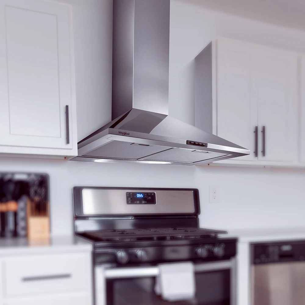 Campana extractora Whirlpool de pared tipo chimenea, con acabado metálico plateado, frente inclinado y dos filtros rectangulares inferiores. - Vista 2